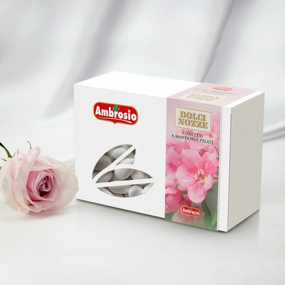 A box of Ambrosio Confetti Sugar Covered Almonds (12x1Kg case) is elegantly displayed alongside a pink rose, featuring a clear window through pink floral adornments that offer a sweet preview of the almond treasures inside.