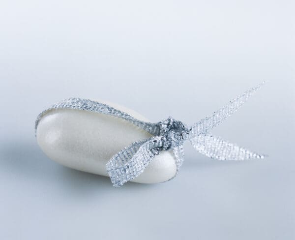 A soap bar, shaped like the iconic Ambrosio Confetti Sugar Covered Almonds, is elegantly tied with a silver ribbon and set against a light gray background.