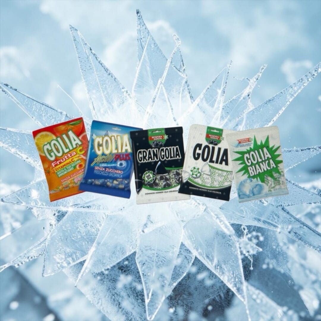 Individually wrapped Golia candies with green and white packaging rest on fir branches and ice, creating a festive, wintry scene.