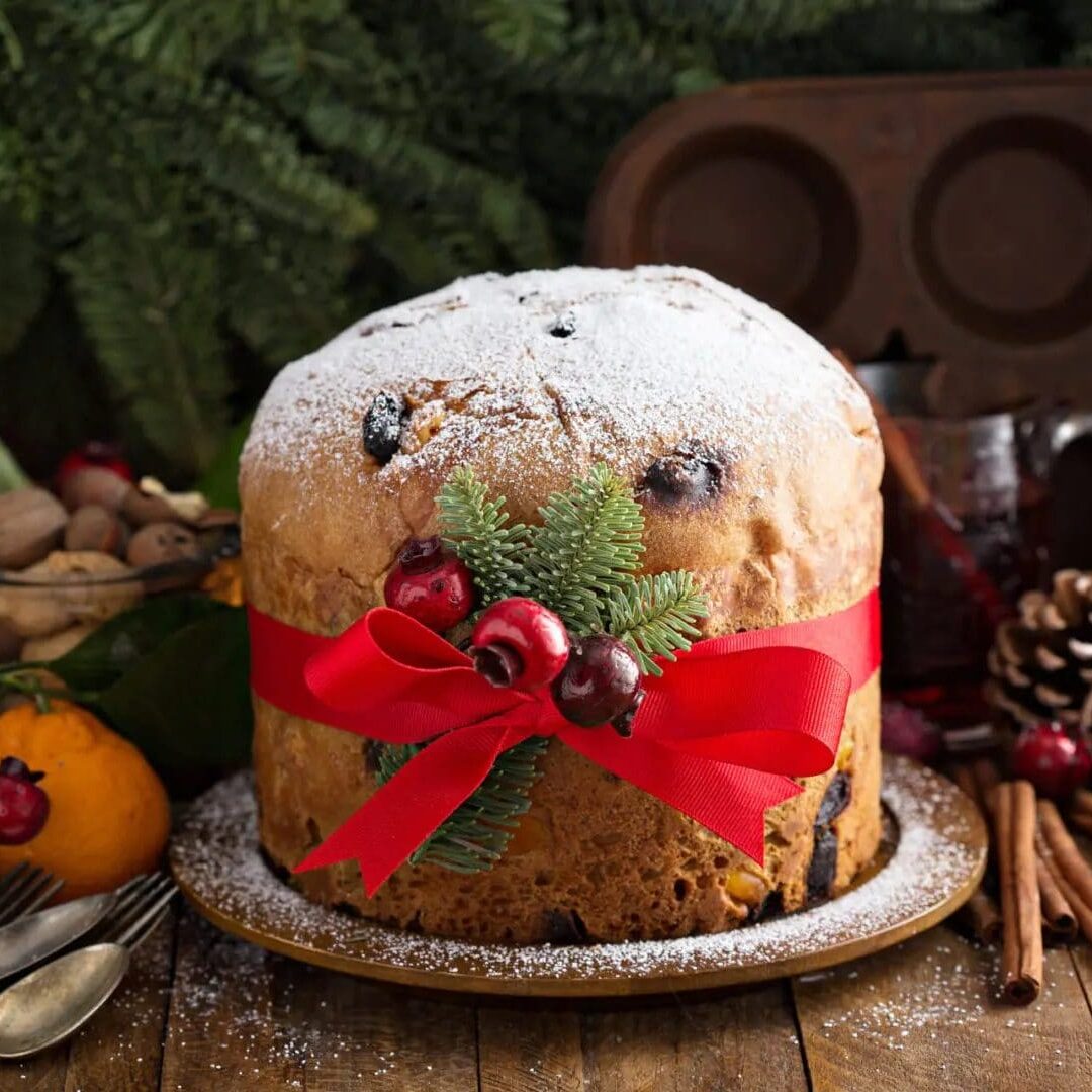 Traditional Christmas panettone with dried fruits and orange zest on rustic background